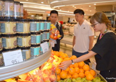 At retailer 3hrsixty in Hong Kong Sam Sin (white shirt) from Freco Int. Hong Kong, who are importers from around the world, showing Vietnam exporters from Central Retail retail and Thailand importer the local retail setup. They are looking at what is in season now and on display for them to export to Hong Kong.